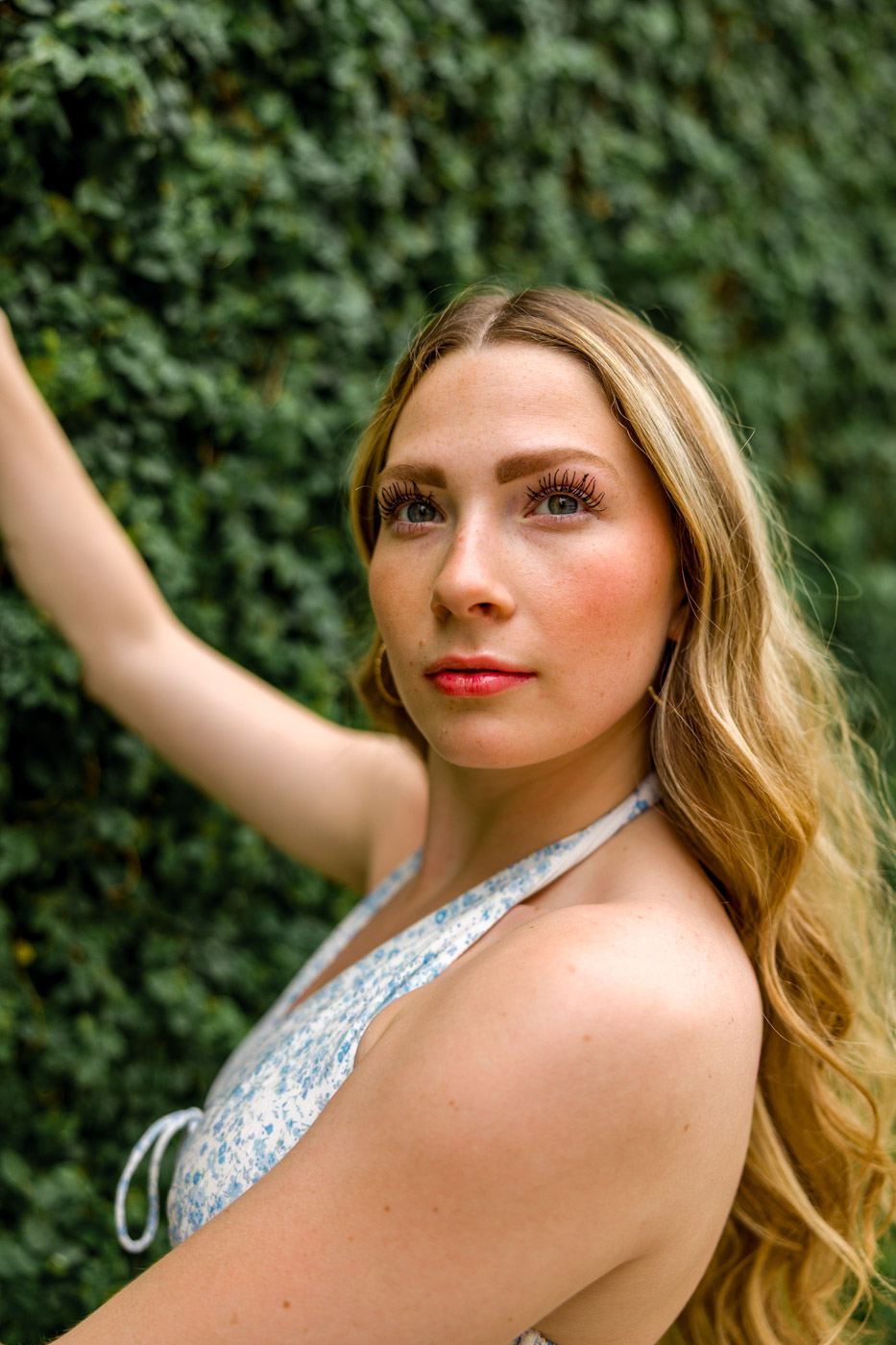 Brynley's senior portrait against the green leaves wall at The Domain